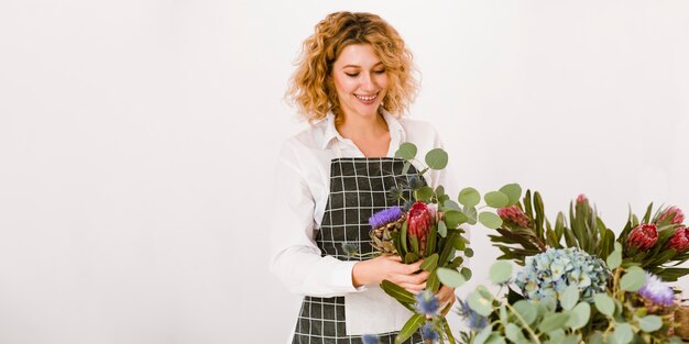 Mittlere Schussglückliche Frau, die einen Blumenstrauß bildet