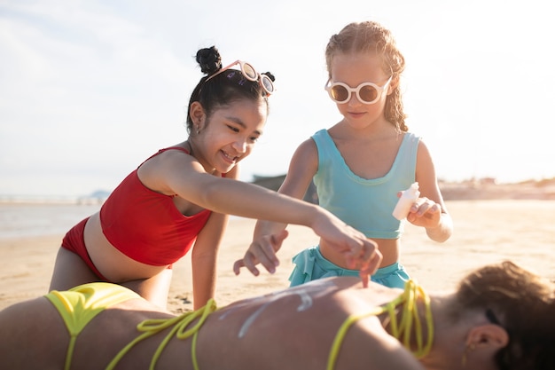 Kostenloses Foto mittlere schusskinder, die sonnencreme auf frau auftragen