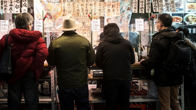 Mittlere schussleute, die an japanischem straßenlebensmittelrestaurant essen