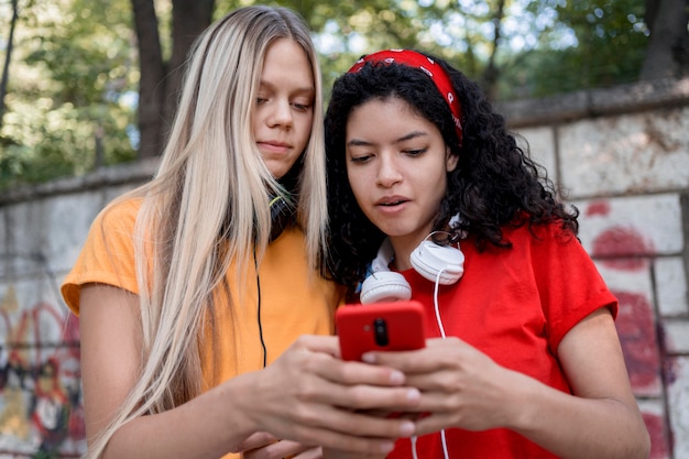 Mittlere Schussmädchen, die Telefon betrachten