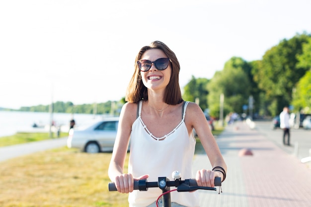 Mittlere Schusssmileyfrau, die einen Roller reitet