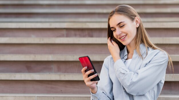 Mittlere Triebblondine, die am Telefon schauen