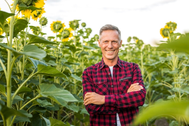 Kostenloses Foto mittlerer ansichtmann auf einem feld von sonnenblumen