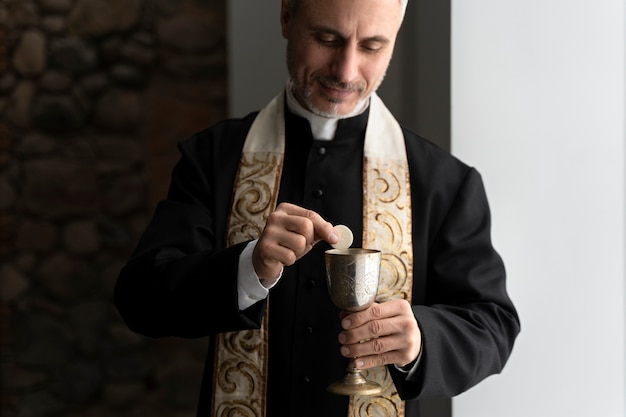 Mittlerer Aufnahmepriester, der Eucharistie hält