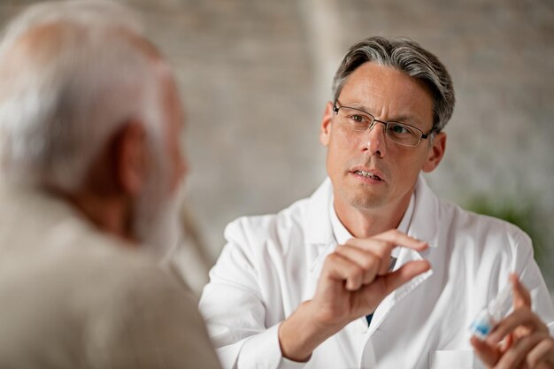 Mittlerer erwachsener Arzt, der sich mit älteren Patienten über verschreibungspflichtige Medikamente in der Klinik berät