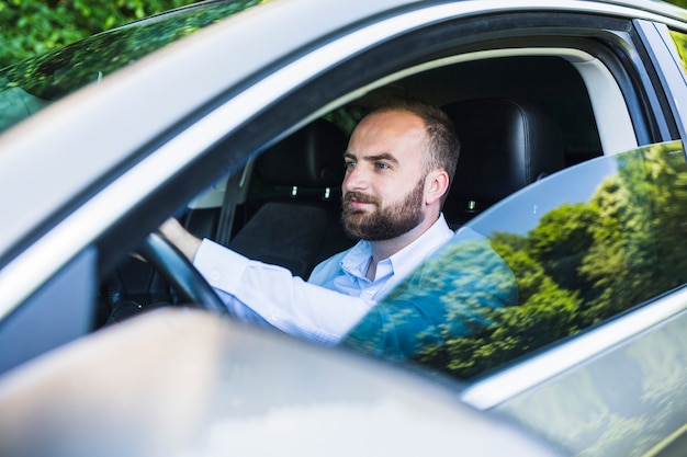 Mittlerer erwachsener Mann, der innerhalb des Autos sitzt