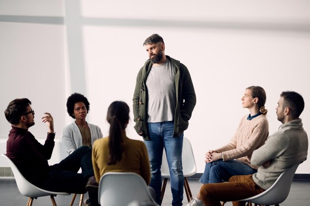 Mittlerer erwachsener Mann, der während der Gruppentherapie im Gemeindezentrum über sich selbst spricht