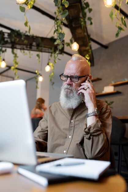 Mittlerer Schuss älterer Mann, der am Telefon spricht