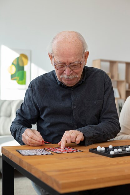 Mittlerer Schuss älterer Mann, der Bingo spielt