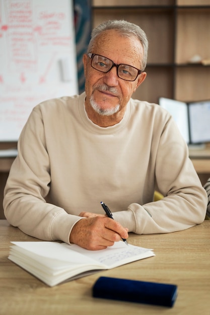 Mittlerer Schuss älterer Mann, der im Klassenzimmer studiert