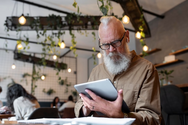 Mittlerer Schuss älterer Mann, der mit Tablet studiert