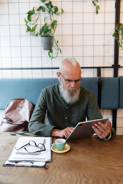 Mittlerer Schuss älterer Mann, der mit Tablet studiert