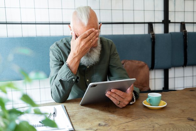 Mittlerer Schuss älterer Mann mit Tablet