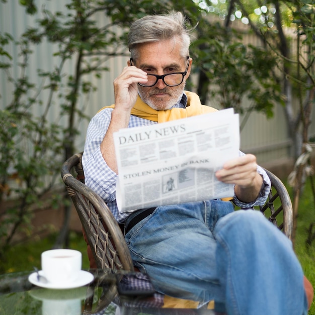 Mittlerer Schuss alter Mann, der Zeitung liest