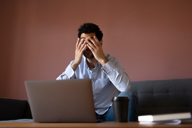 Kostenloses Foto mittlerer schuss besorgter mann, der mit laptop arbeitet