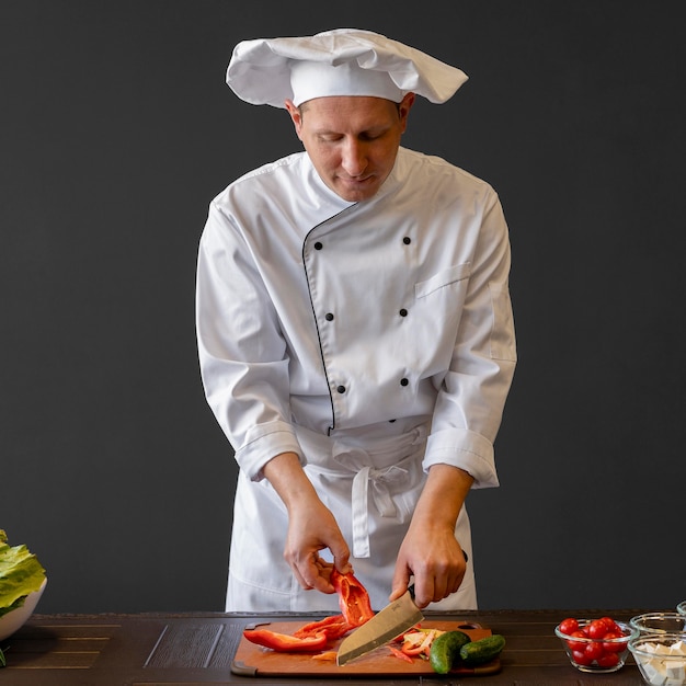 Kostenloses Foto mittlerer schuss chef, der paprika schneidet