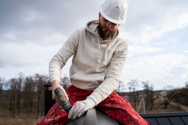Mittlerer Schuss Dachdecker, der mit Schutzhelm arbeitet