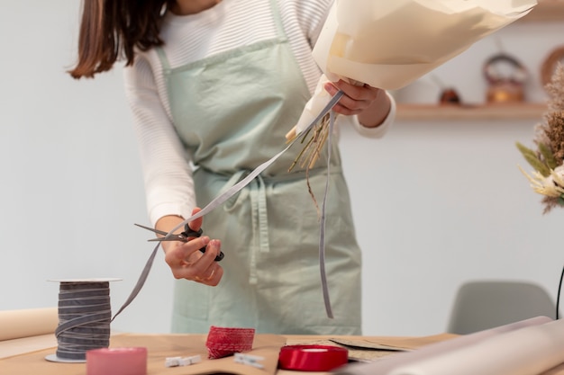 Mittlerer Schuss der Arbeiterfrau, die einen Blumenstrauß schafft