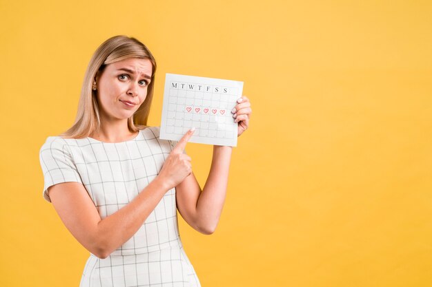 Mittlerer Schuss der Frau den Zeitraumkalender zeigend