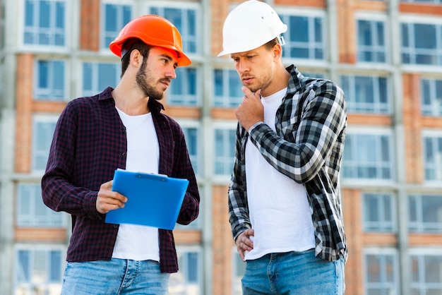 Kostenloses Foto mittlerer schuss der ingenieur- und bauarbeiterunterhaltung