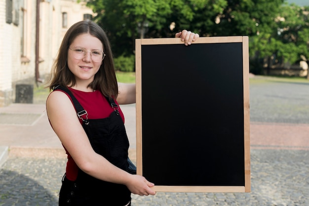 Kostenloses Foto mittlerer schuss der jugendlichen tafel in den händen halten