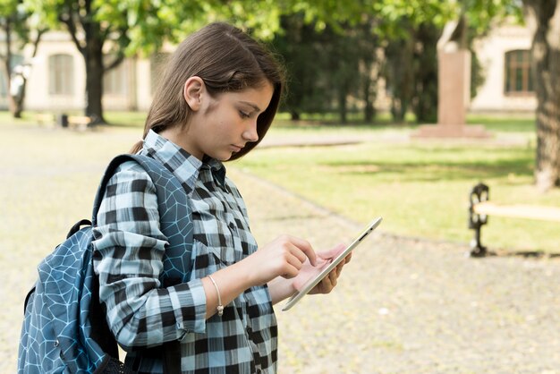 Mittlerer Schuss der Seitenansicht des Schulmädchens, das Tablette verwendet