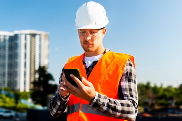 Mittlerer Schuss des Ingenieurs Telefon betrachtend