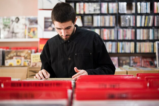 Mittlerer Schuss des jungen Mannes Vinyls im Speicher suchend