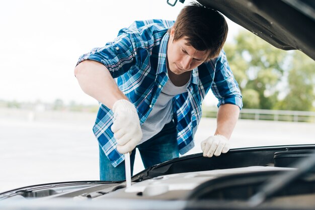 Mittlerer Schuss des Mannes arbeitend an Auto