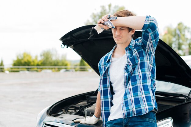 Mittlerer Schuss des Mannes mit Auto im Hintergrund