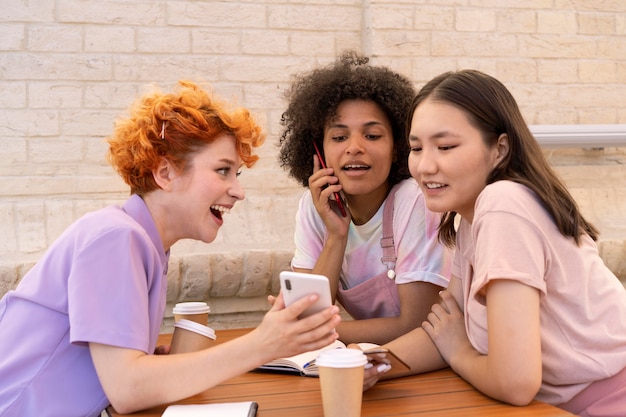 Mittlerer Schuss glückliche Freunde mit Telefon