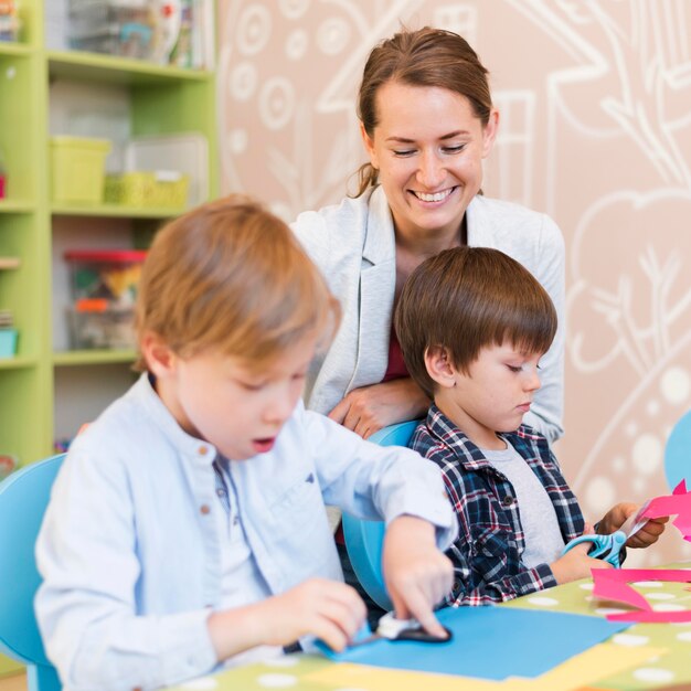 Mittlerer Schuss glücklicher Lehrer, der Kinder beobachtet