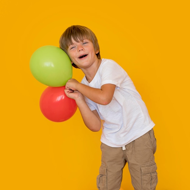 Kostenloses Foto mittlerer schuss junge, der luftballons hält