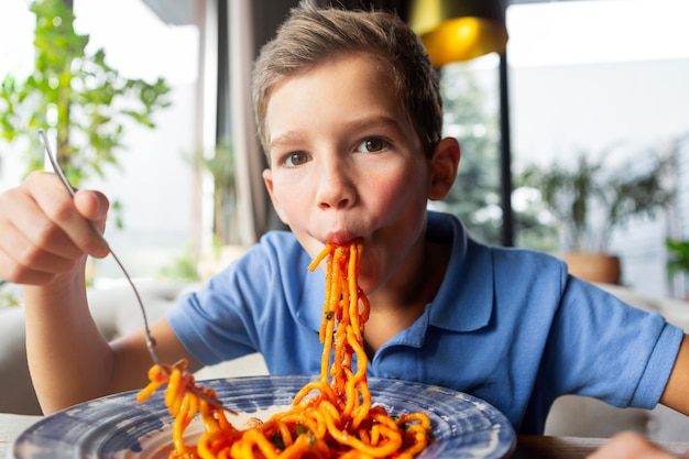 Mittlerer Schuss Junge, der Spaghetti isst