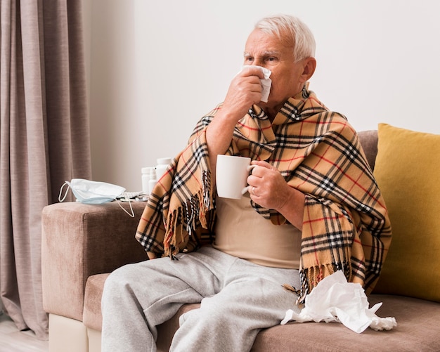 Kostenloses Foto mittlerer schuss kranker mann, der tasse hält