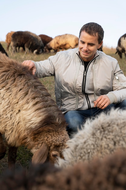 Kostenloses Foto mittlerer schuss mann, der schafe streichelt