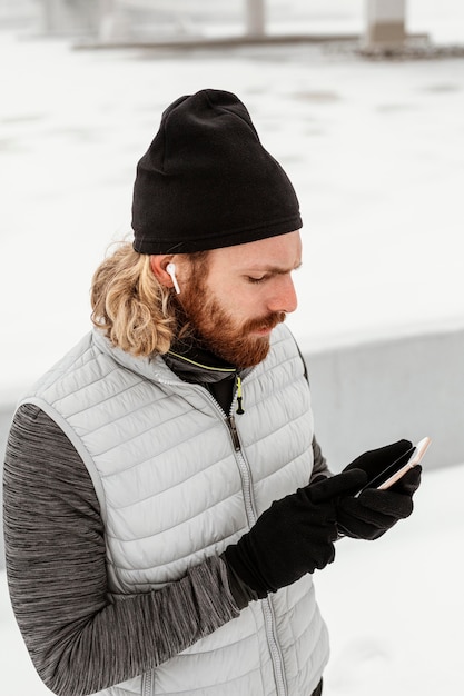 Mittlerer Schuss Mann, der Telefon überprüft