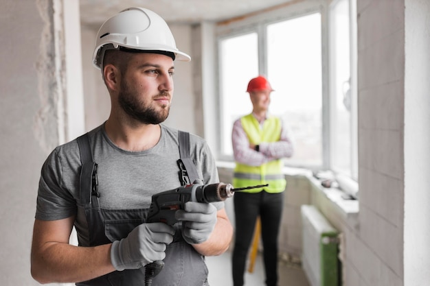 Mittlerer schuss mann mit helm und bohrer