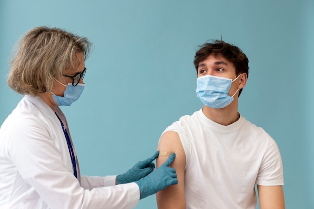 Mittlerer schuss mann mit maske bekommt impfstoff