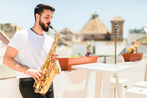 Mittlerer Schuss seitlich Mann, der das Saxophon spielt