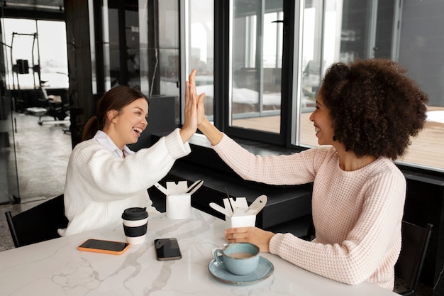 Kostenloses Foto mittlerer schuss smiley frauen high five