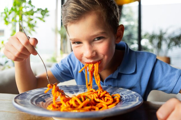 Mittlerer Schuss Smiley Junge, der Spaghetti isst