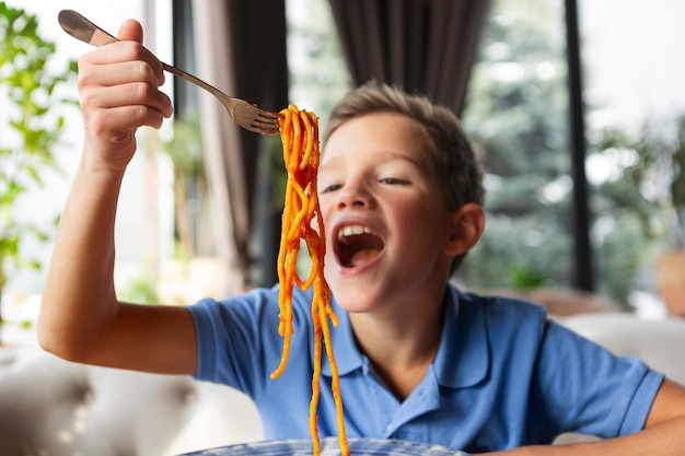 Mittlerer Schuss Smiley-Junge mit Spaghetti