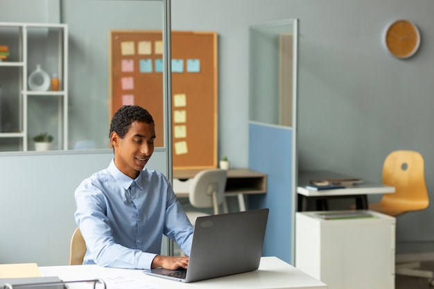 Mittlerer Schuss Smiley-Mann, der am Laptop arbeitet