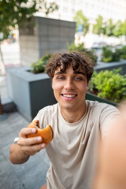 Kostenloses Foto mittlerer schuss smiley-mann, der burger hält