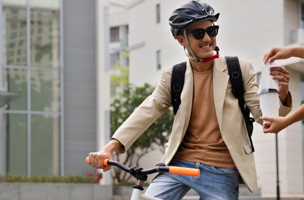 Mittlerer Schuss Smiley-Mann, der mit dem Fahrrad zur Arbeit geht