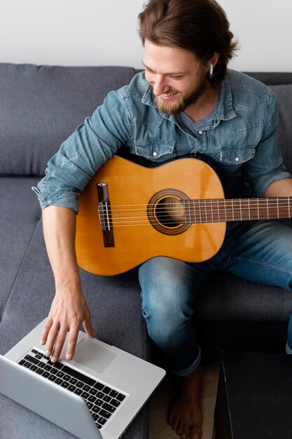 Mittlerer Schuss Smiley-Mann mit Gitarre und Laptop