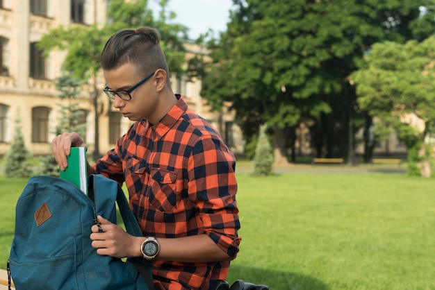 Mittlerer Schuss-Teenager der Seitenansicht, der Buch in Rucksack einsetzt