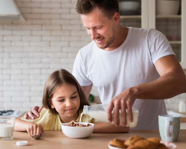 Mittlerer Schuss Vater, der Milch in Schüssel gießt