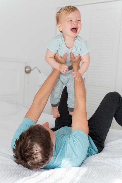 Kostenloses Foto mittlerer schuss vater hält kleinkind hoch